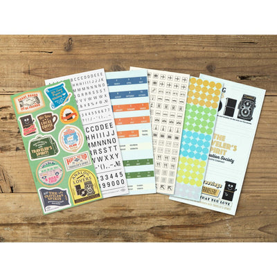 Collection of TRAVELER'S NOTEBOOK 2026 planner stickers on a wooden surface