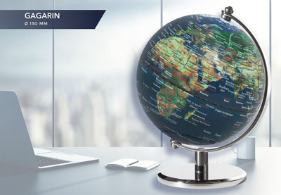 Multi-color Troika 5 inch globe with a laptop and paper on a blurred background 